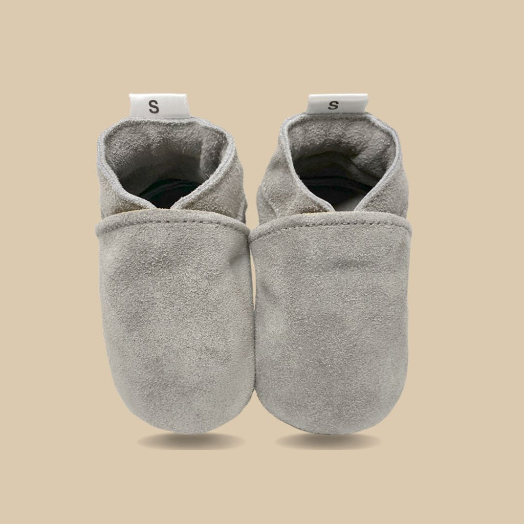 Jongetje met suede babyslofjes zittend op een stoel
